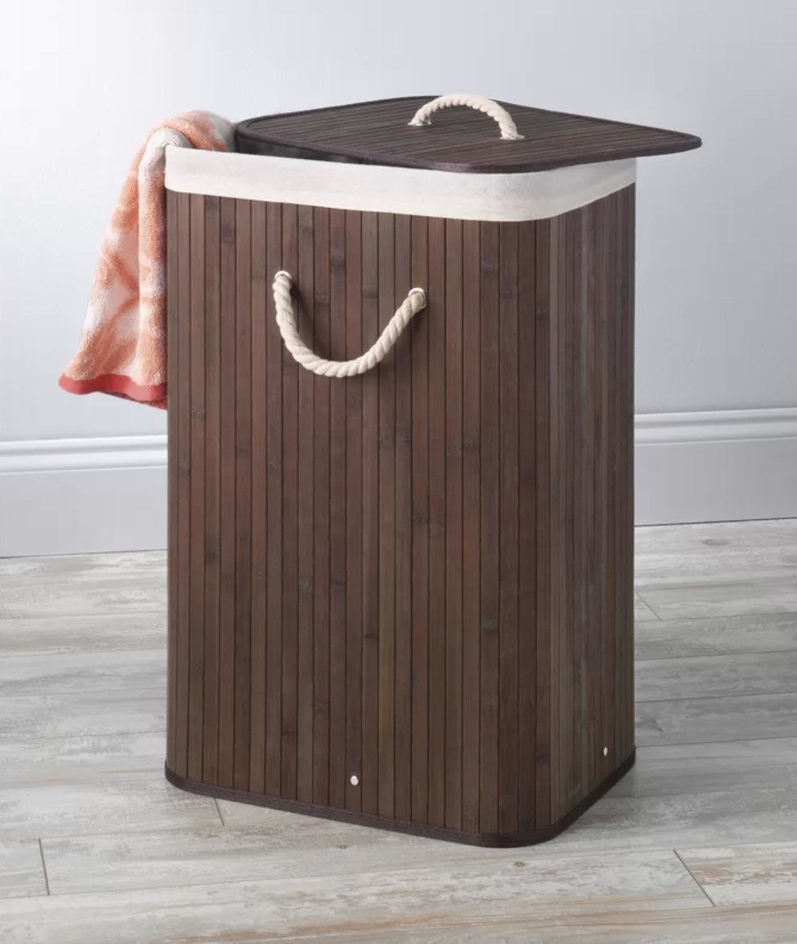 the dark wooden laundry hamper with white rope handles