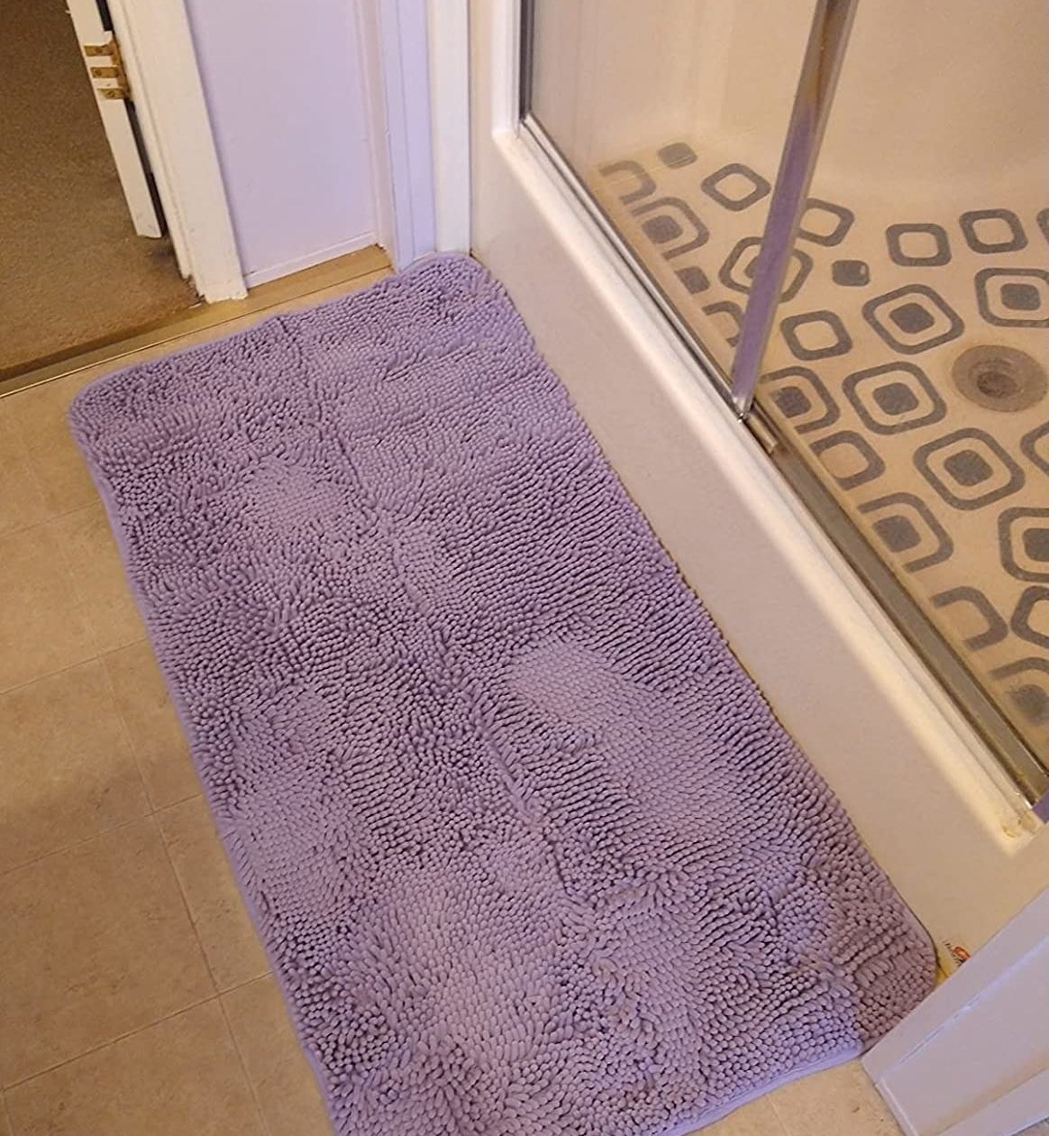a reviewer photo of a purple bathmat on the floor in front of a shower