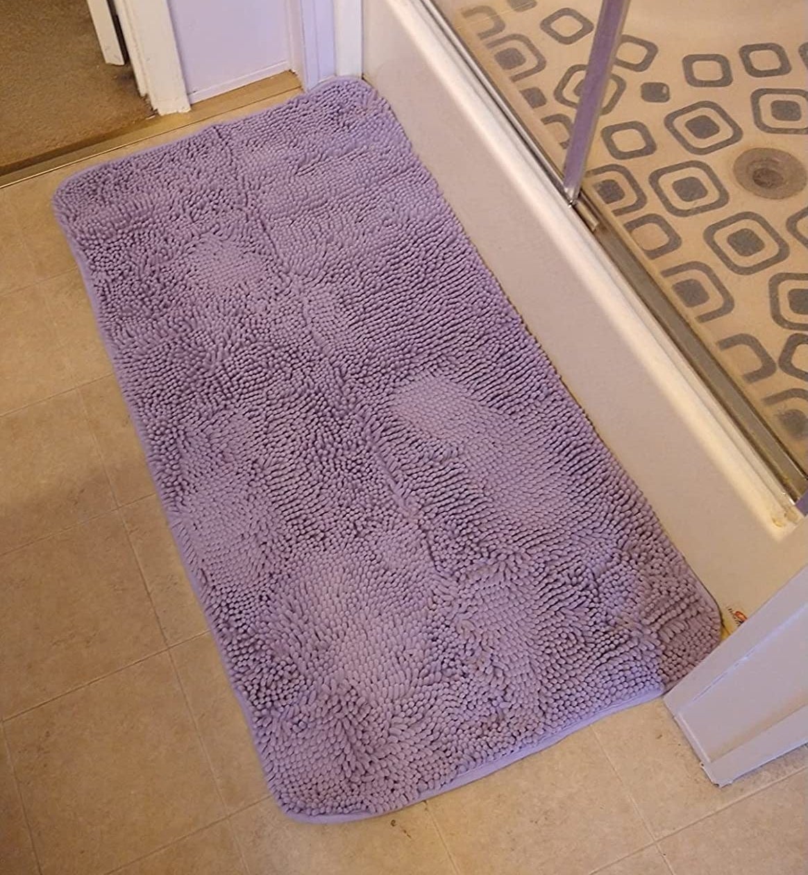 a reviewer photo of a purple bathmat on the floor in front of a shower