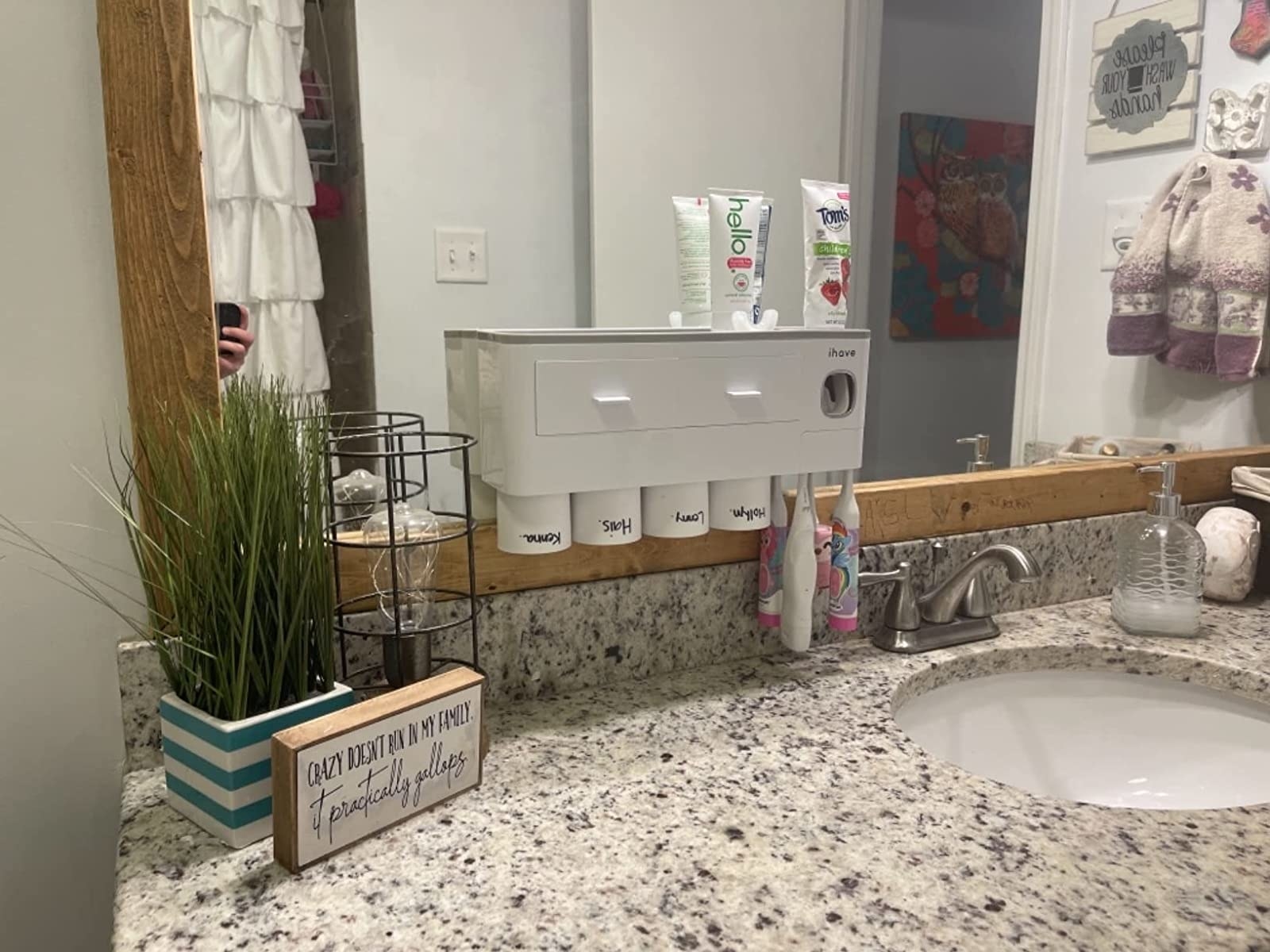 a reviewer photo of the white caddy attached to the mirror in a decorated bathroom space