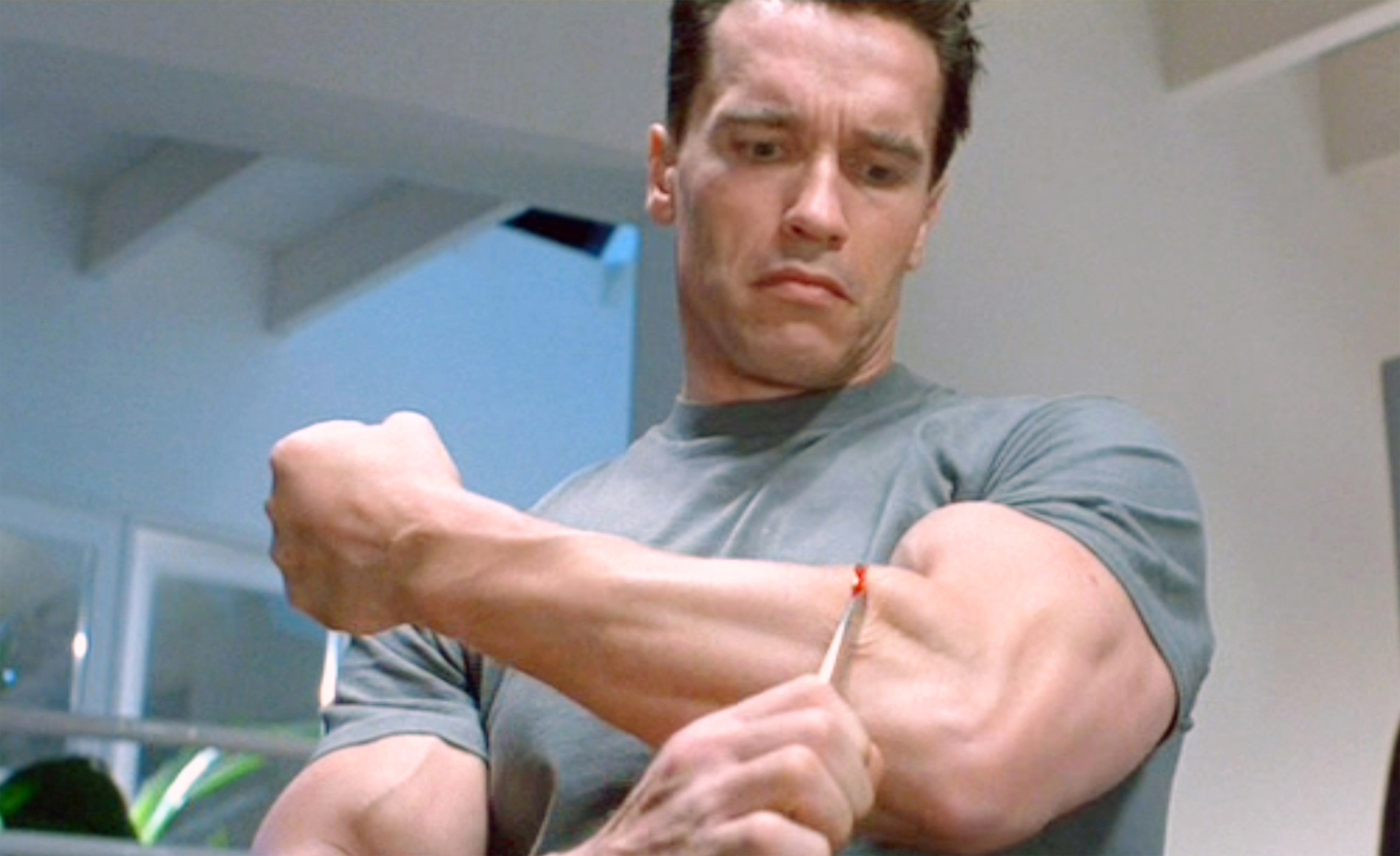 Arnold Schwarzenegger (as the T-800 Terminator) begins to cut the living tissue of his forearm to reveal metal endoskeleton