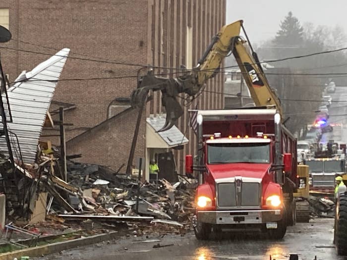 A busy street scene with rubble, trucks and cranes, and workers