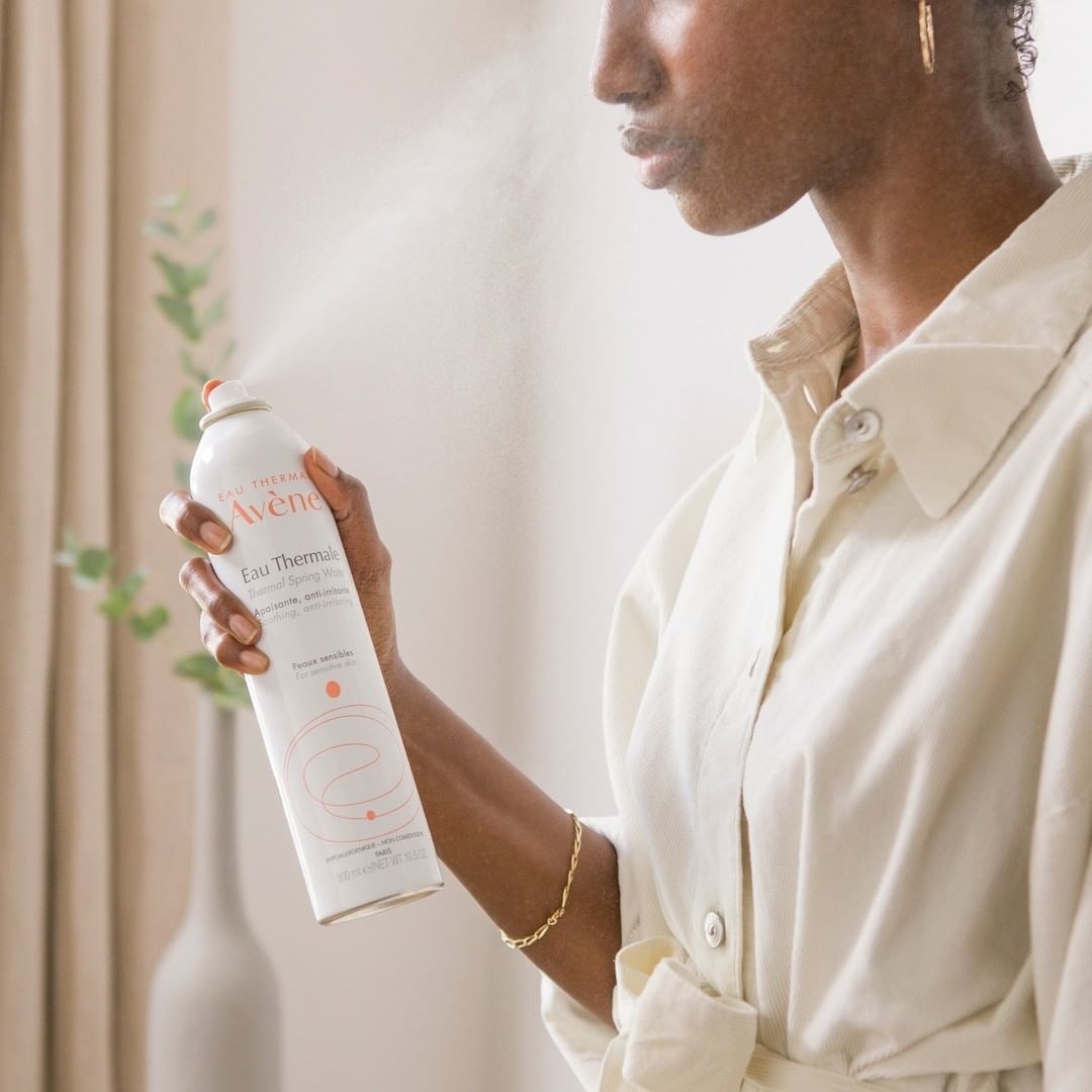 A person holding a bottle of the thermal spray