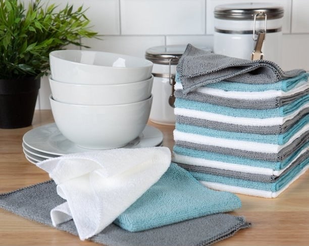 a set of blue, white, and gray microfiber cleaning towels next to a set of white plates and bowls