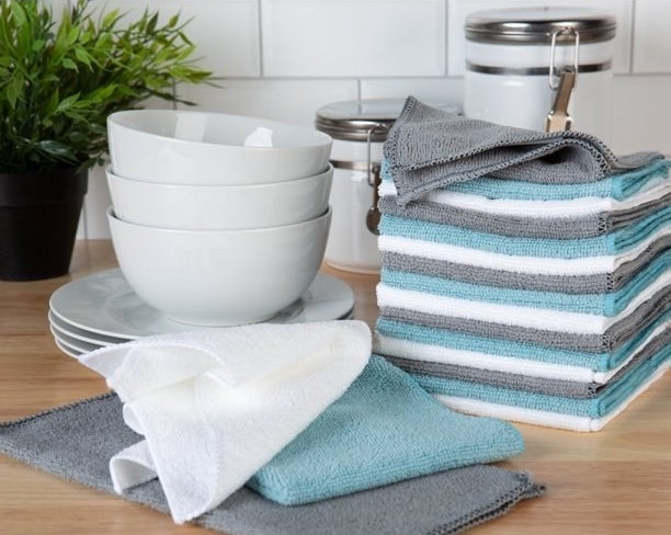 a set of blue, white, and gray microfiber cleaning towels next to a set of white plates and bowls