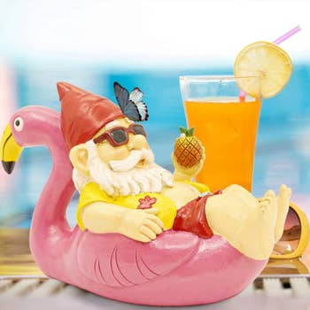 a gnome in a hawaiian shirt, holding the pineapple, and reclining on a pink flamingo