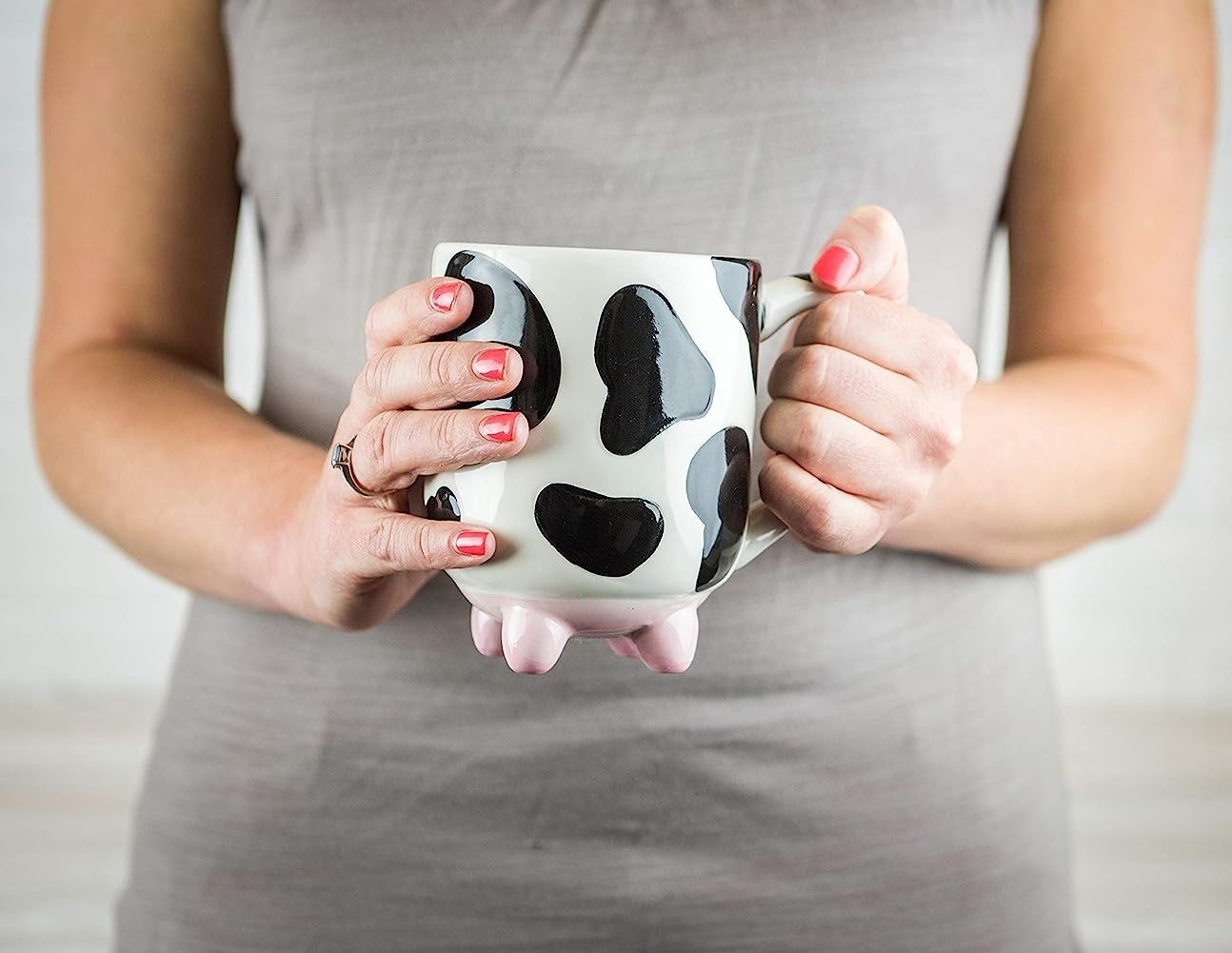 someone holding a large cow print mug with udder feet