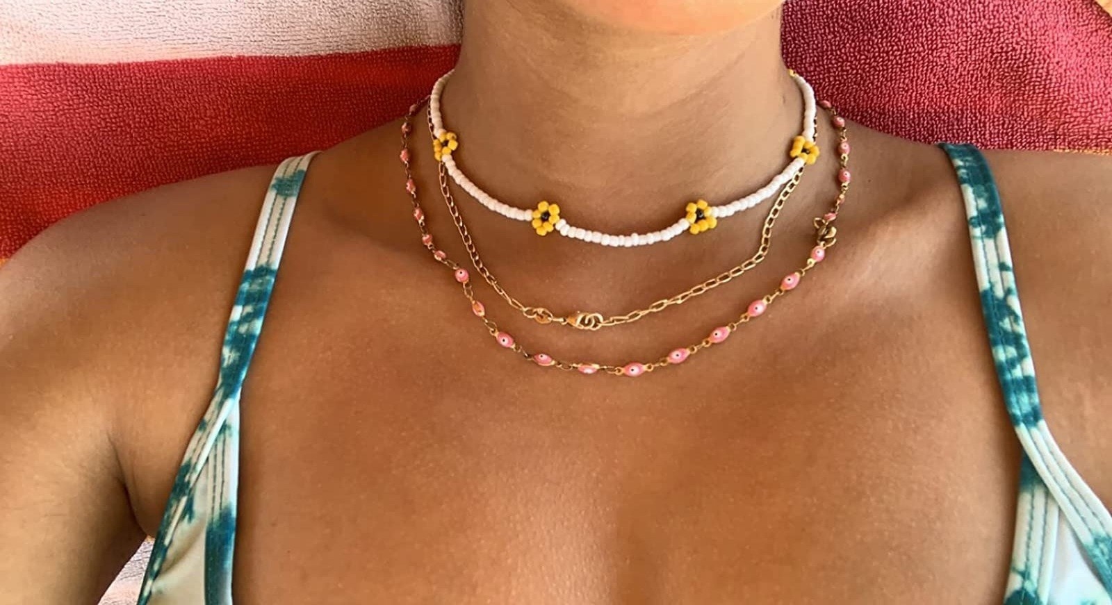 Reviewer wearing the white necklace with yellow flowers and a pink and gold chain as well