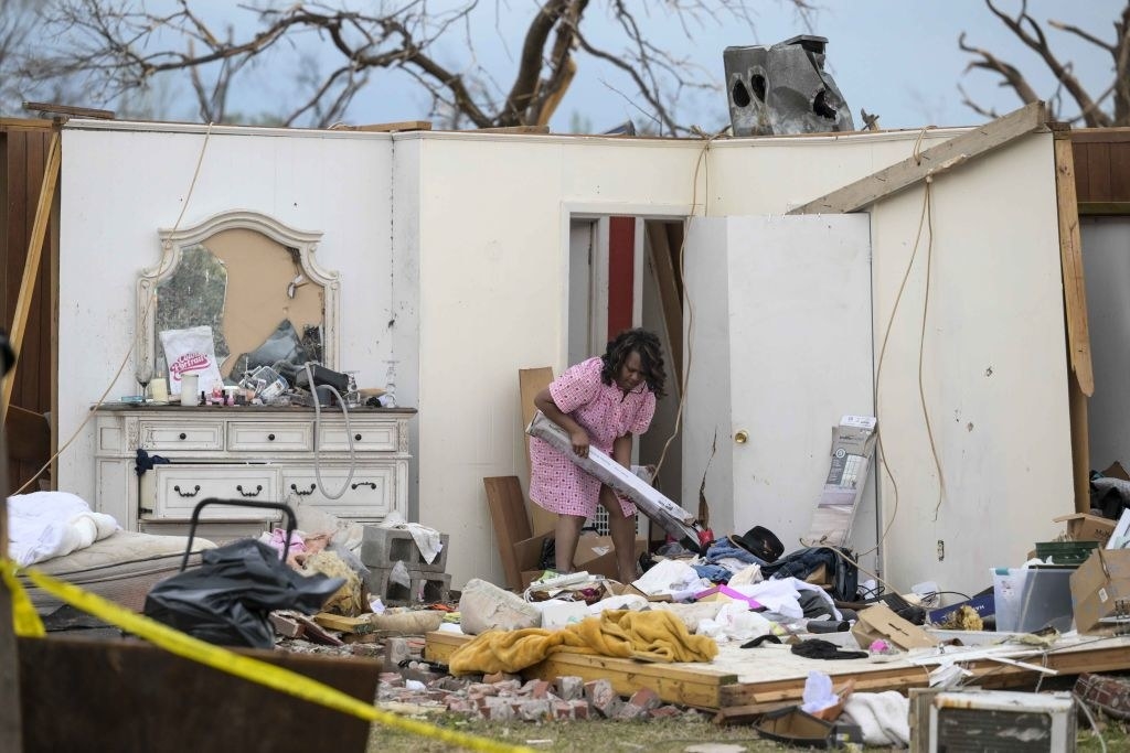 A person sifts through the rubble of the bedroom which only has one wall left