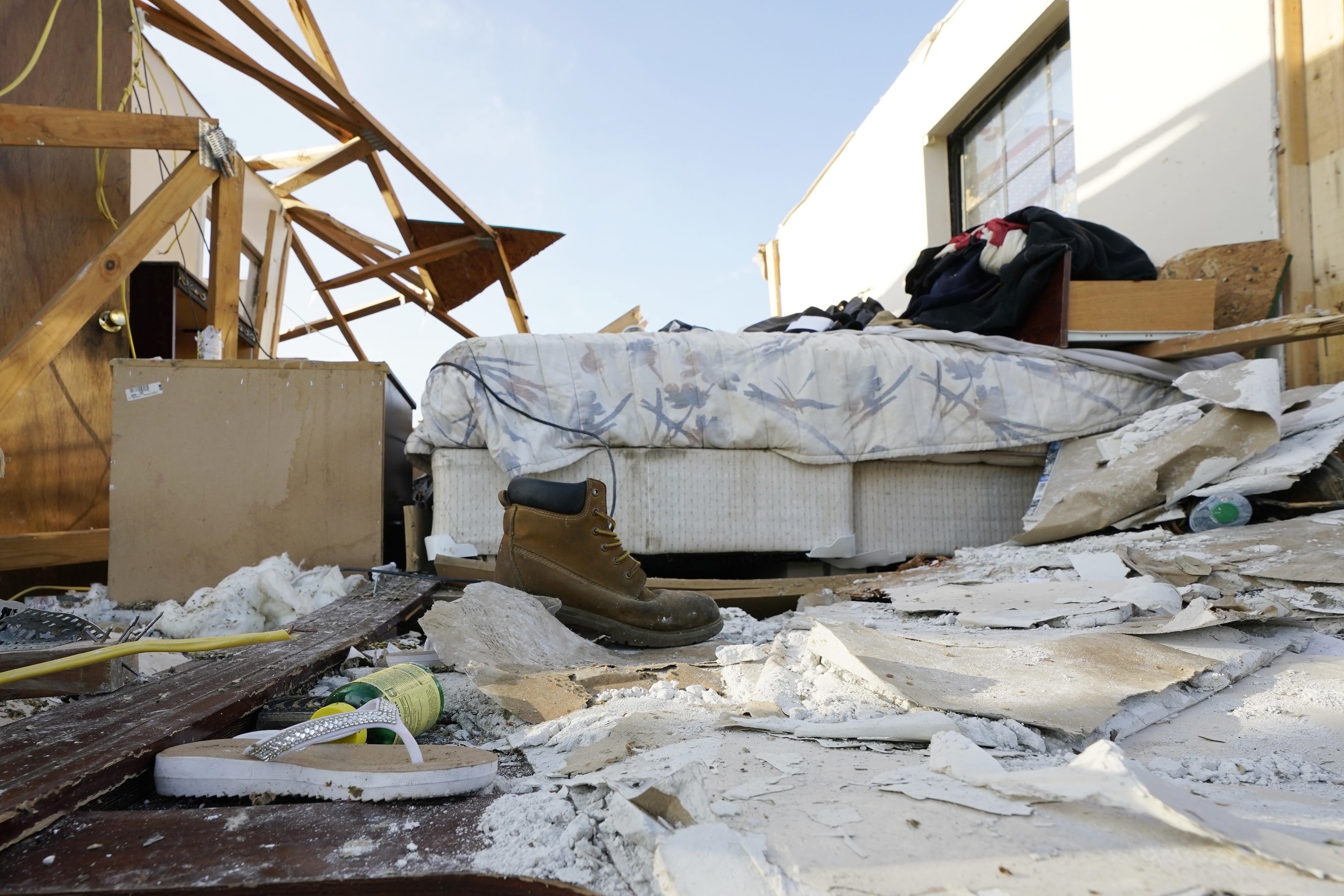 A bedroom that no longer has walls or a roof. Items have been strewn everywhere