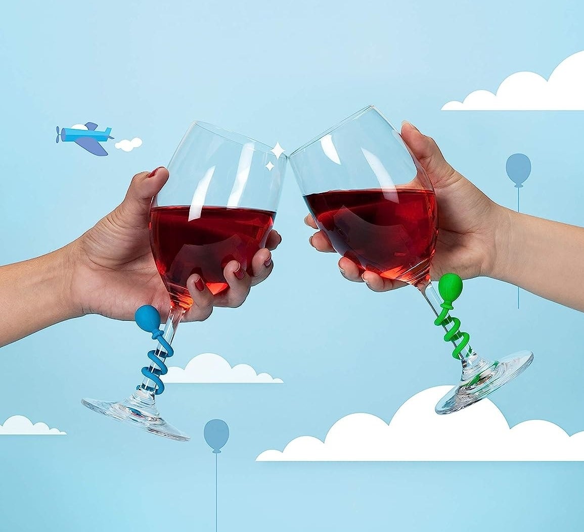 two people clinking their wine glasses together with the drink charms wound around the stem