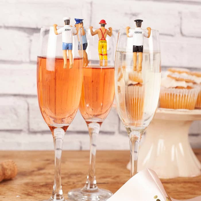 four human shaped wine glass markers on champagne flutes