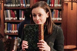 Rory from Gilmore Girls holding an old book in a library