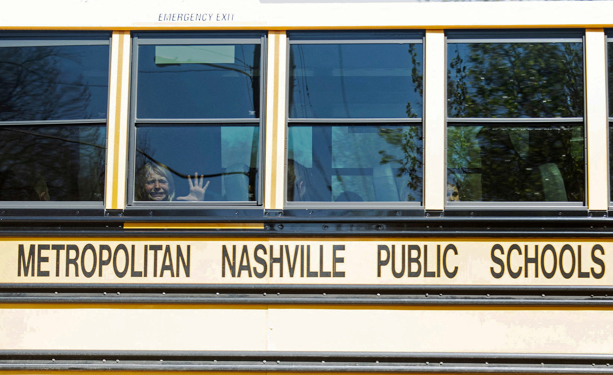 a crying child looks out the window of a school bus labeled &quot;metropolitan nashville public schools&quot;