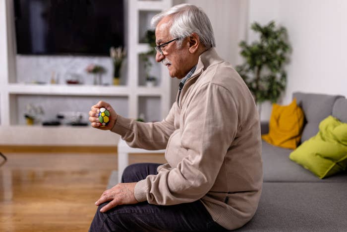 A man sitting on a couch in a living room holding a stress ball