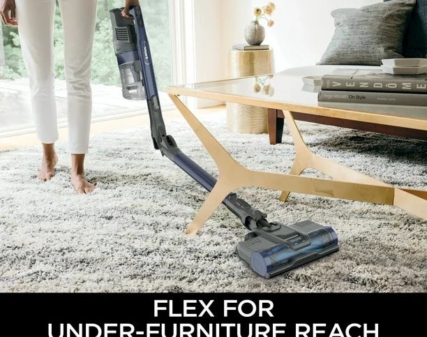 A model using the vacuum to clean under a coffee table