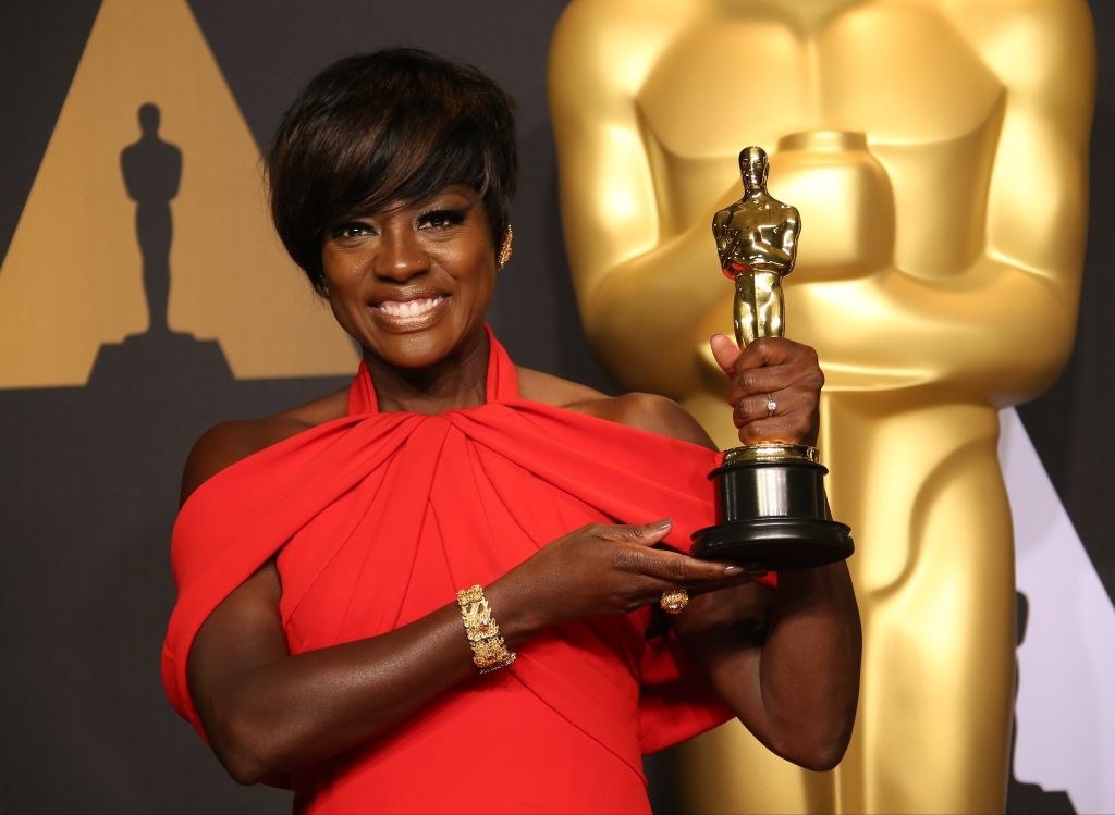 Viola smiling and holding up an award