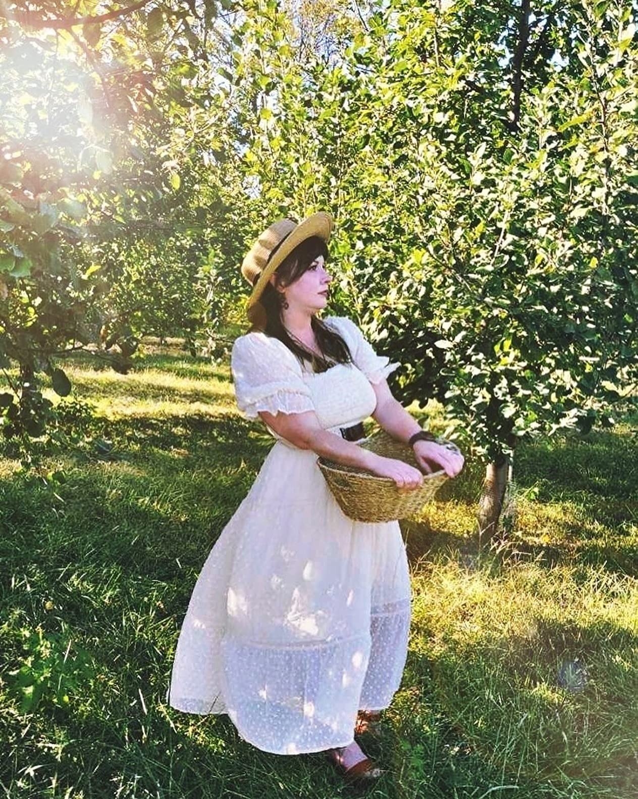 a reviewer wearing the white dress and a straw hat