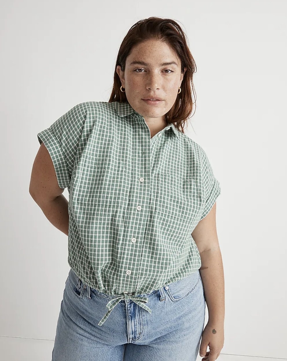 A person wearing a green and white plaid short sleeve shirt
