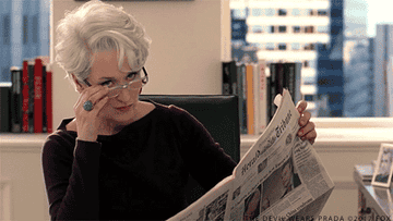 Miranda Priestly from &quot;The Devil Wears Prada&quot; takes off her glasses as she&#x27;s reading a newspaper at her desk and looks at someone
