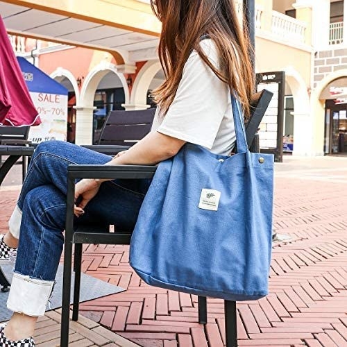 a person sitting at an outdoor table with the bag around their shoulder