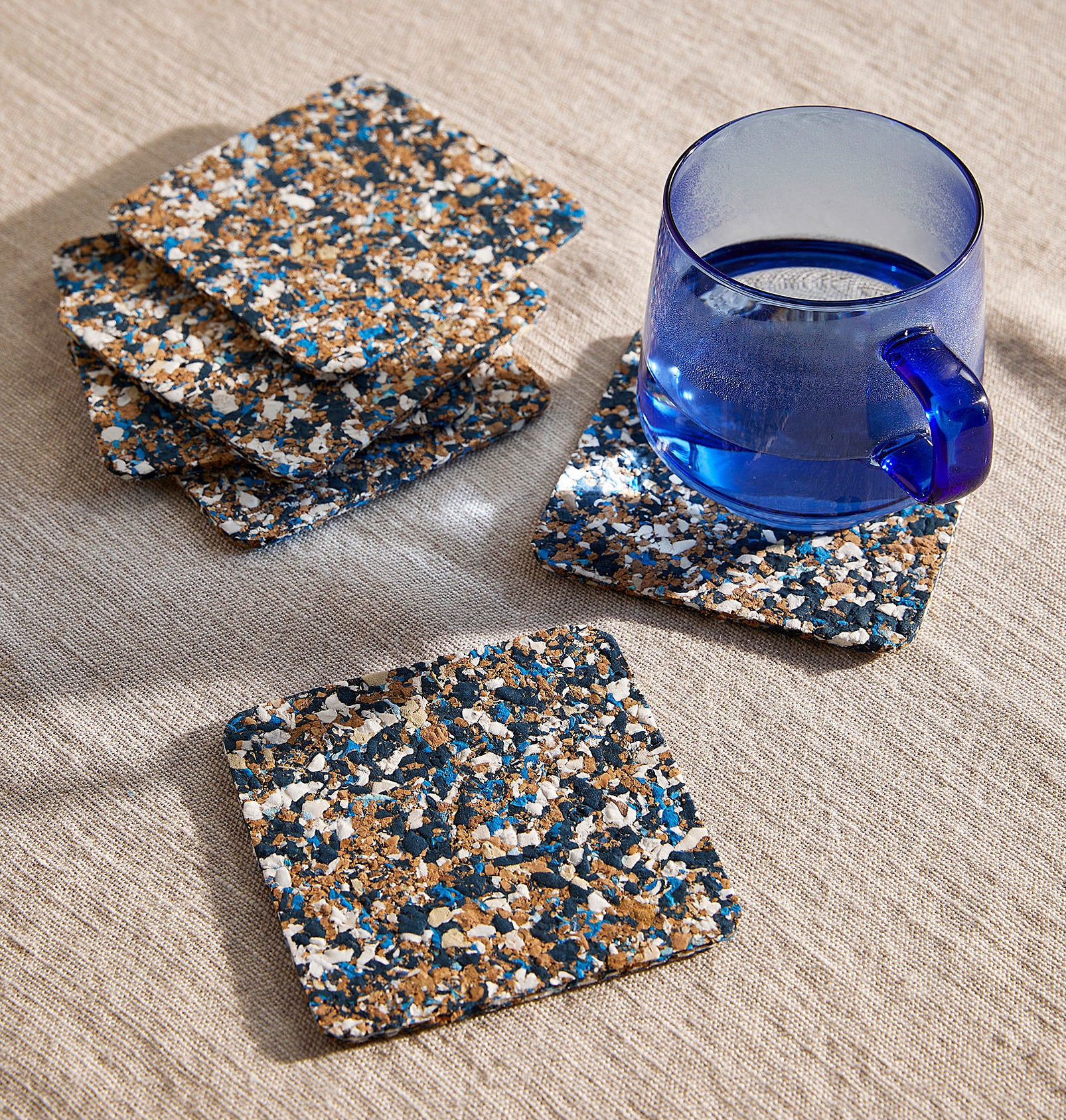 a set of square cork terrazzo coasters on a tablecloth