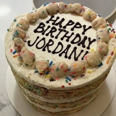 A cake with vanilla frosting that says happy birthday jordan