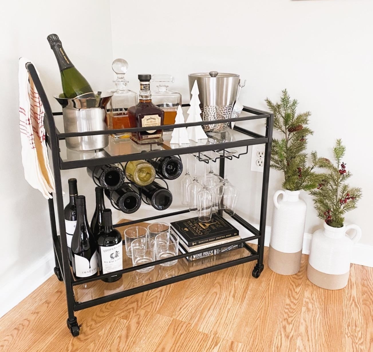 Reviewer&#x27;s bar cart is shown with a bunch of bottles and glasses on it