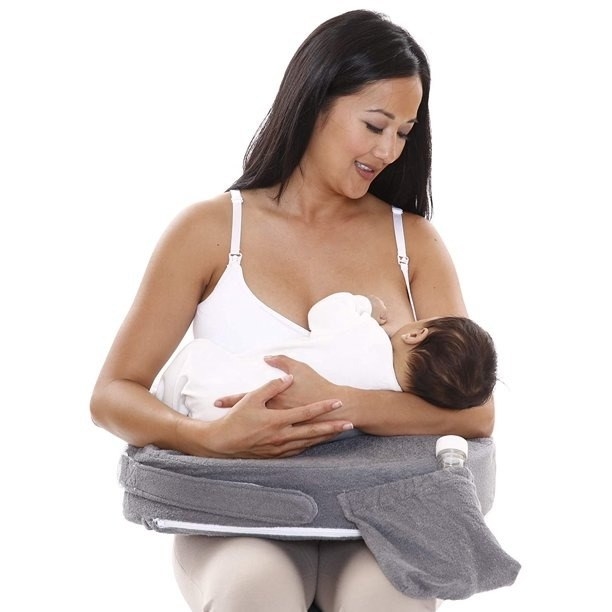 Woman uses nursing pillow to nurse baby