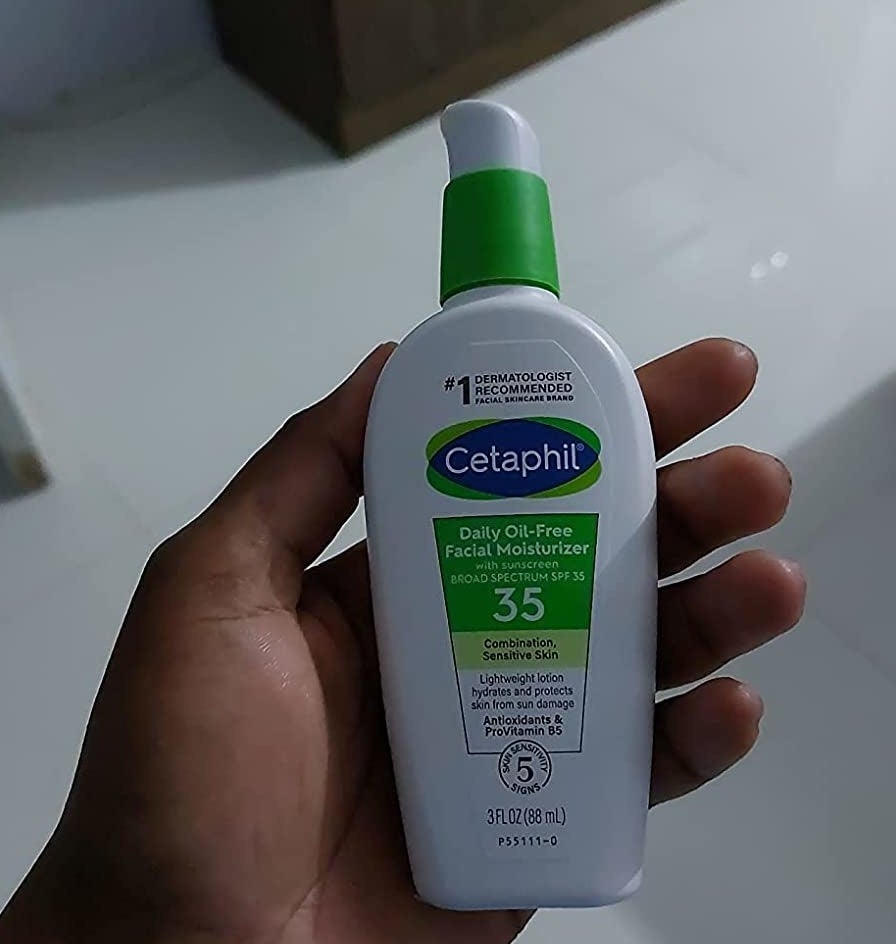 reviewer holding the Cetaphil moisturizer with SPF