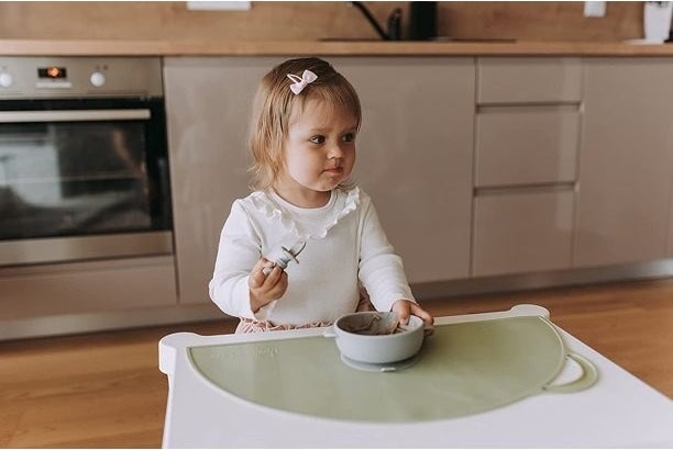 Child eats with a bowl on the mat