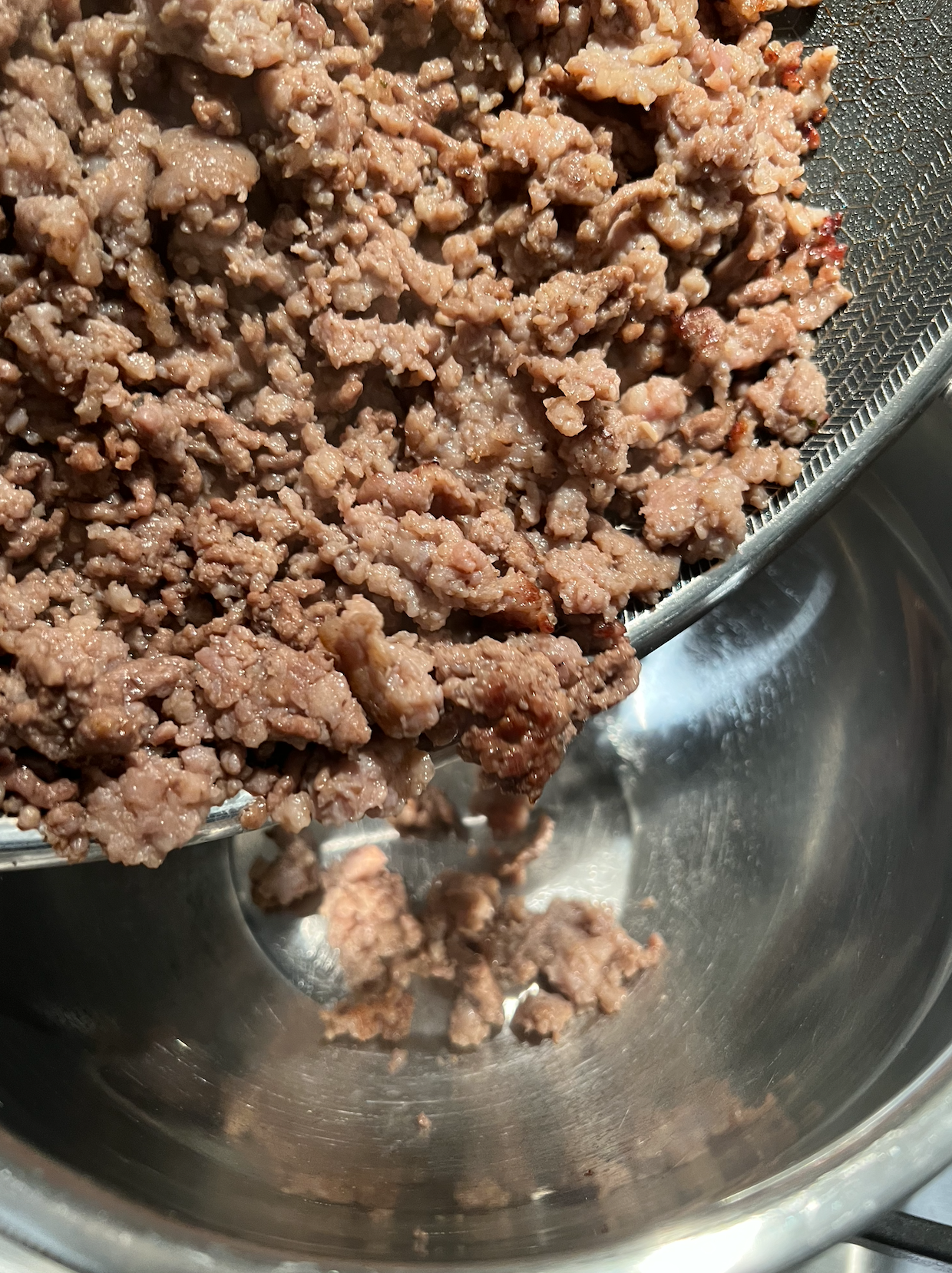 The ground beef being transported into a bowl