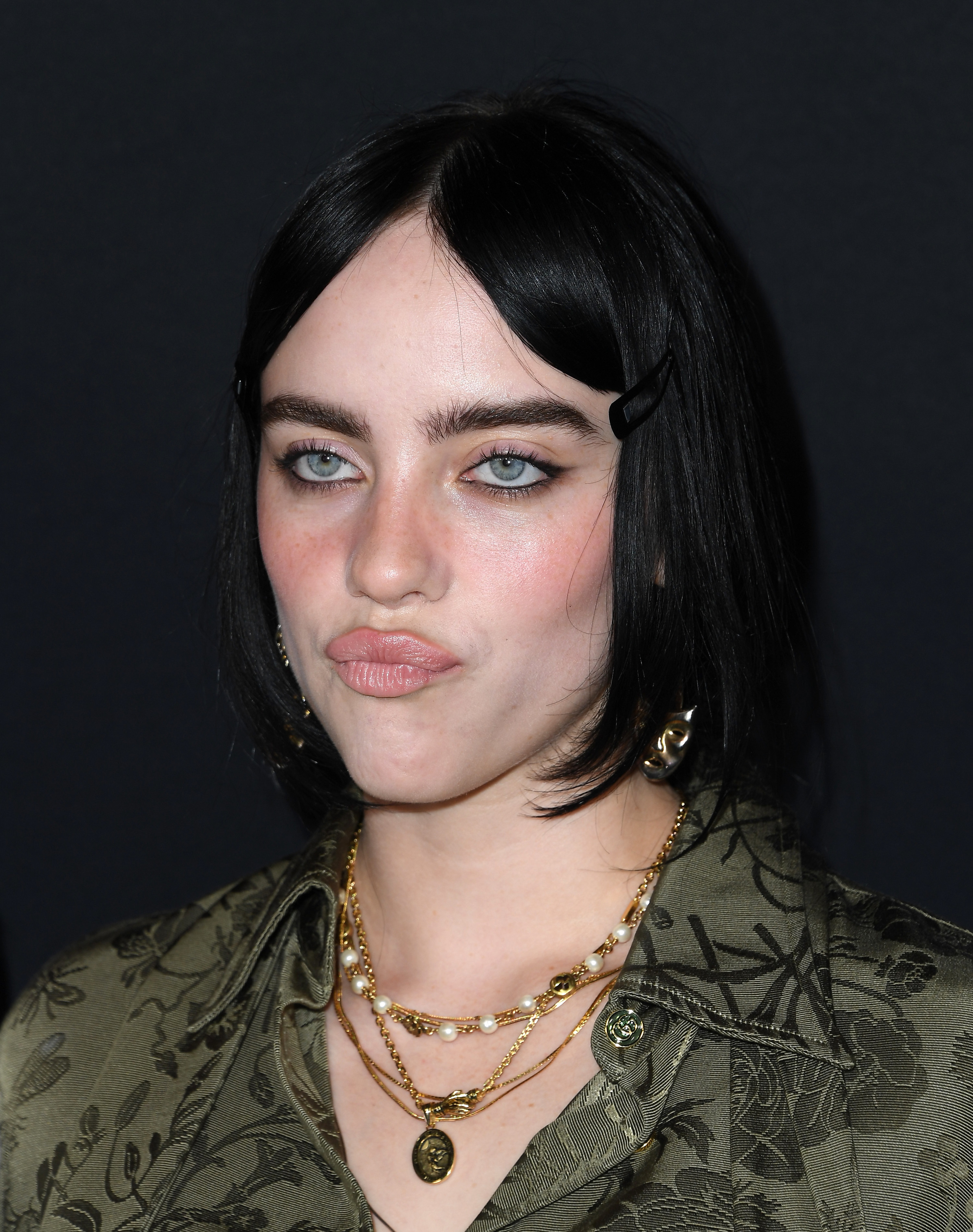 Close-up of Billie pursing her lips and wearing several necklaces