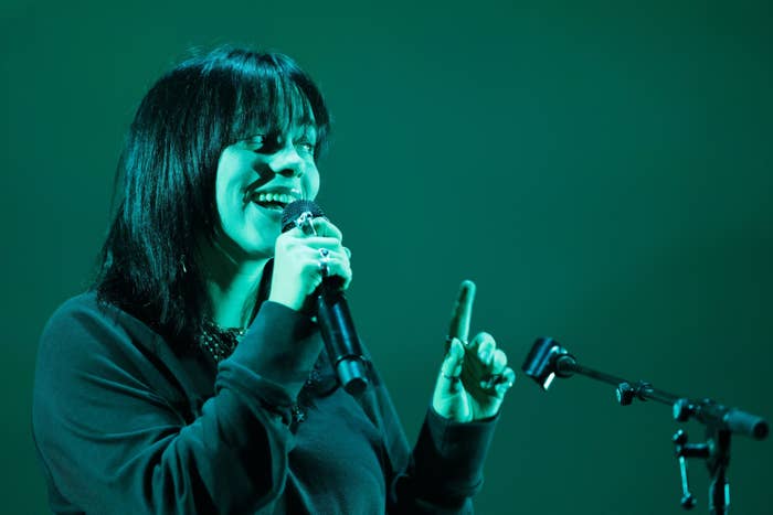 Billie holding a microphone as she stands onstage