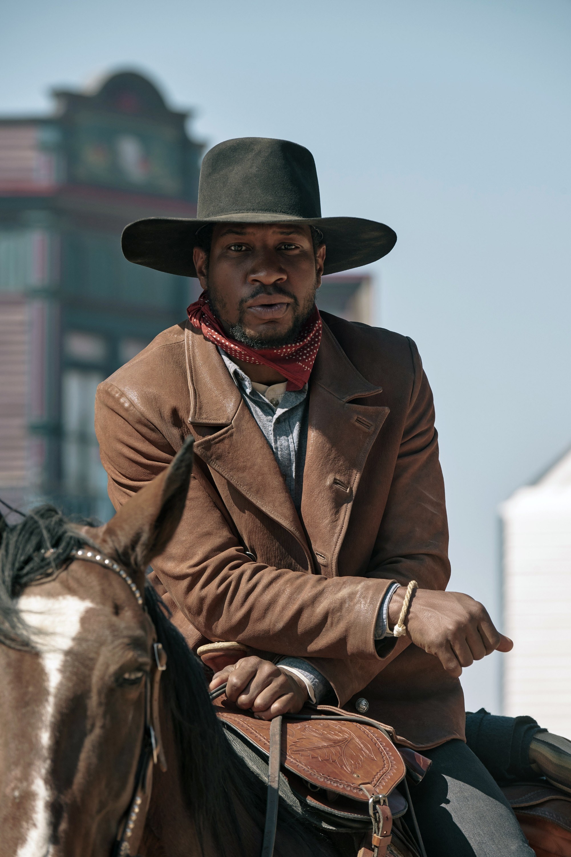 wearing a cowboy hat and jacket while horseback