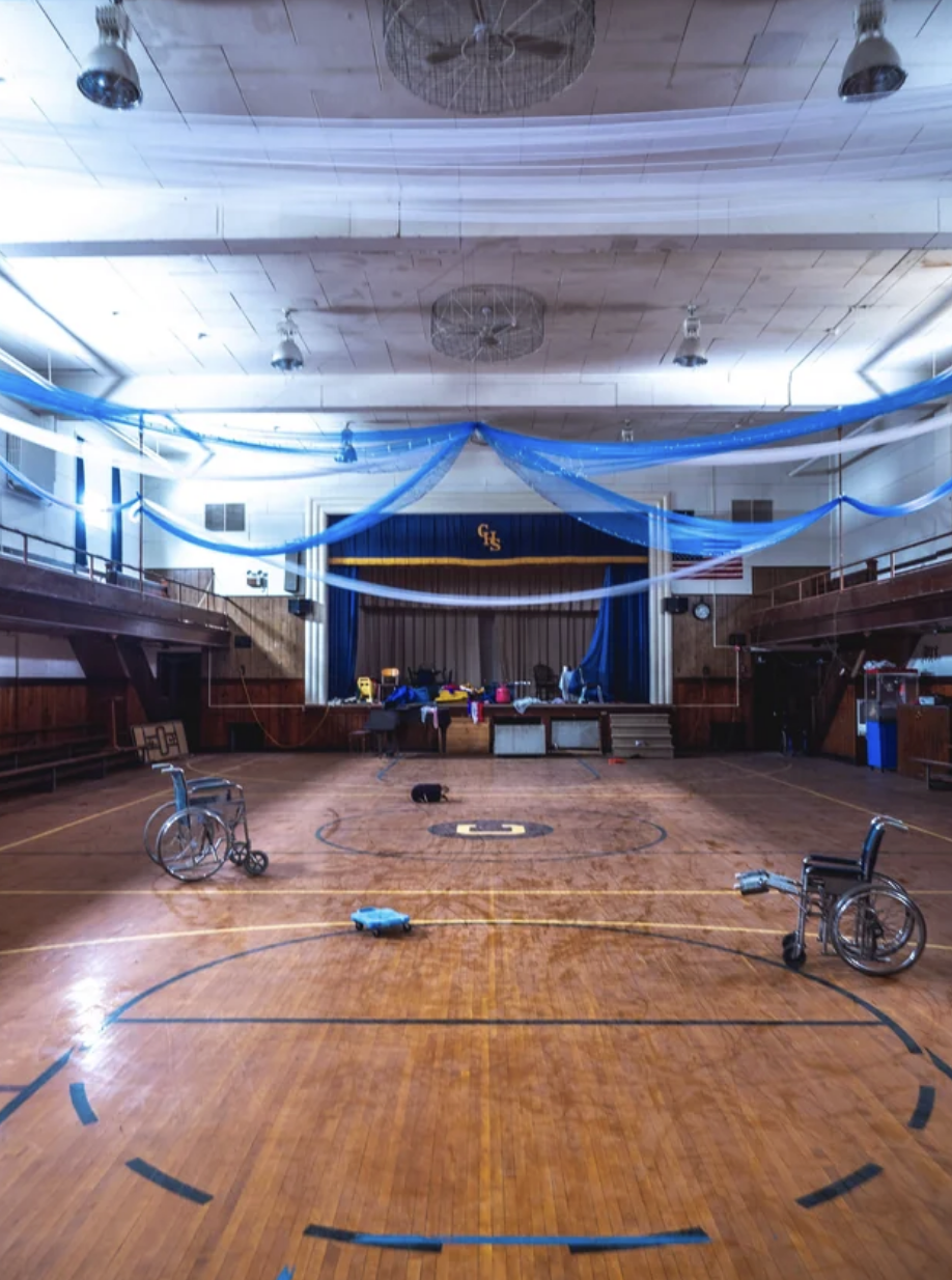 The gym&#x27;s ceiling is still decorated, but it is otherwise empty except for two wheelchairs, giving it an eerie feeling