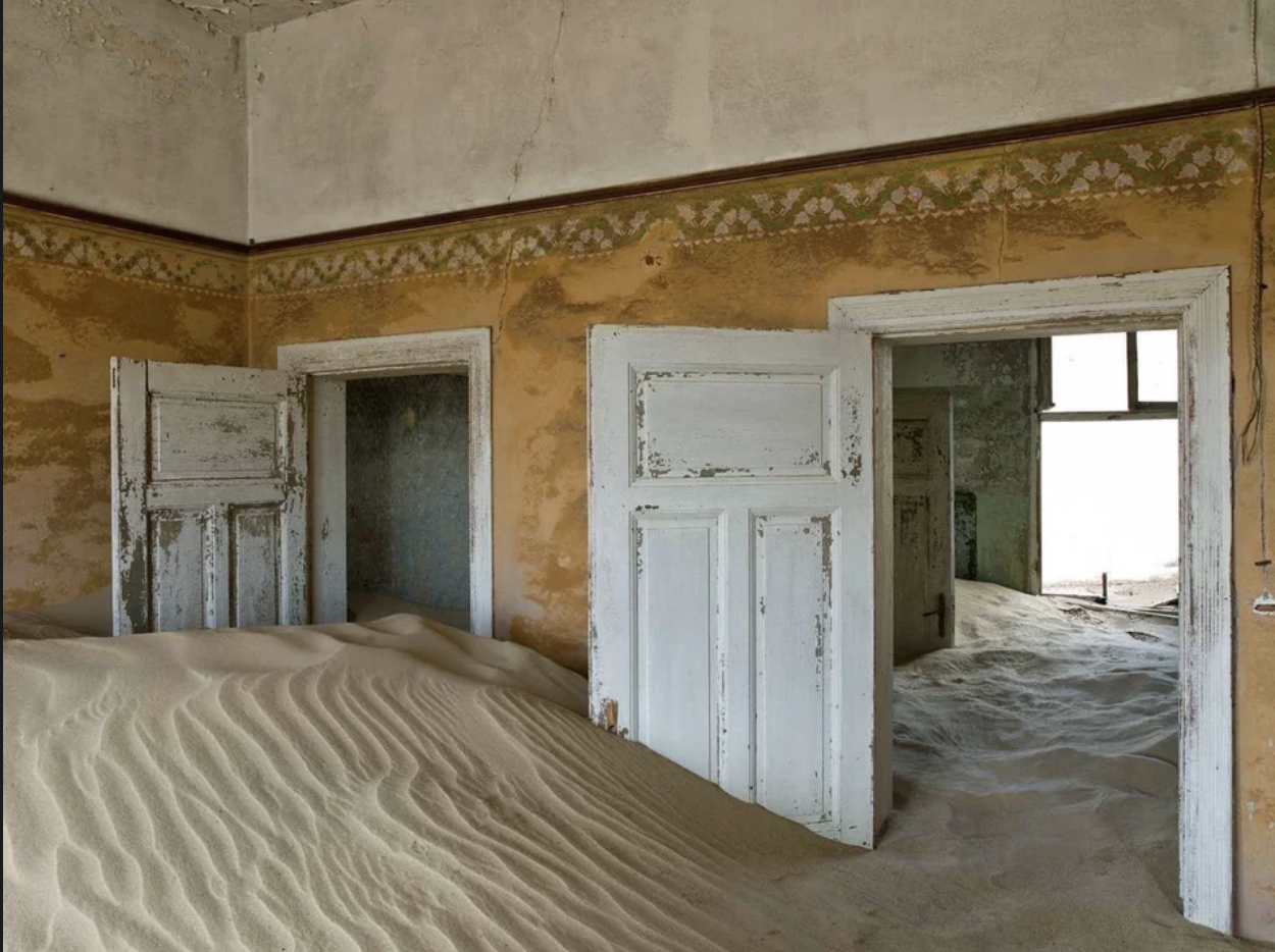 The house has been covered in sand to the point that the sand reaches halfway up the open doors
