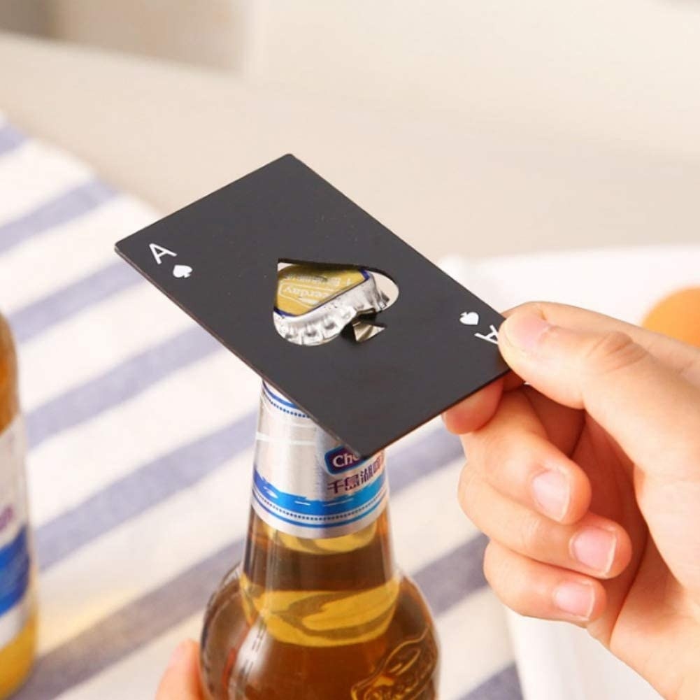 a person opening a bottle with the ace of spades card bottle opener