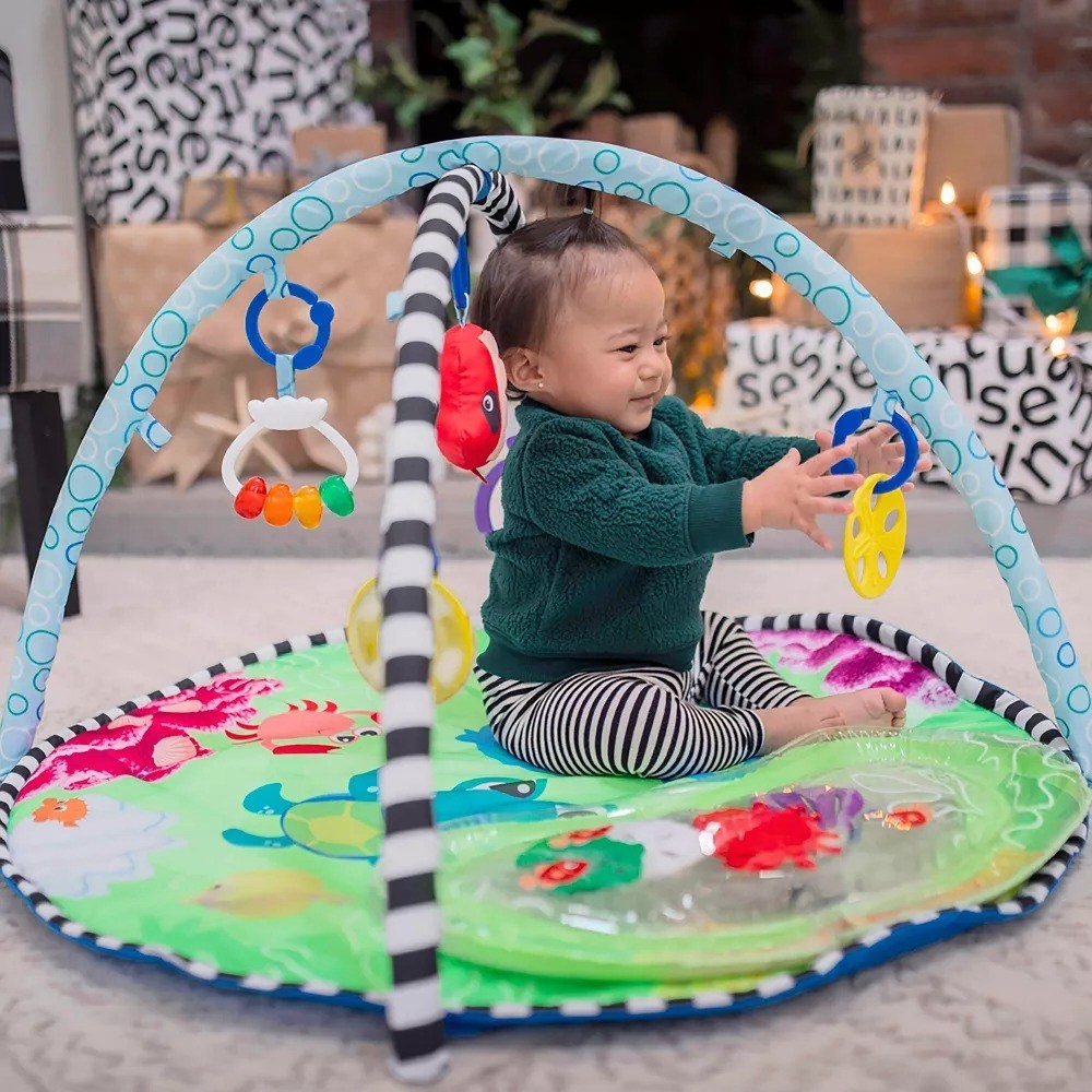 baby playing on the colorful water play mat and activity gym
