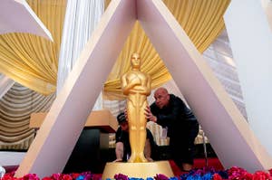 Workers placing an Oscars statue on a red carpet
