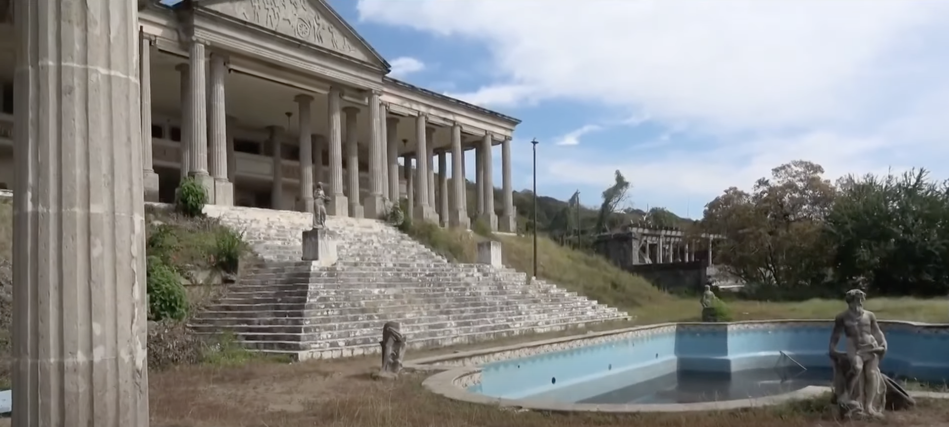 empty pool and a large marble staircase surrounded by statues