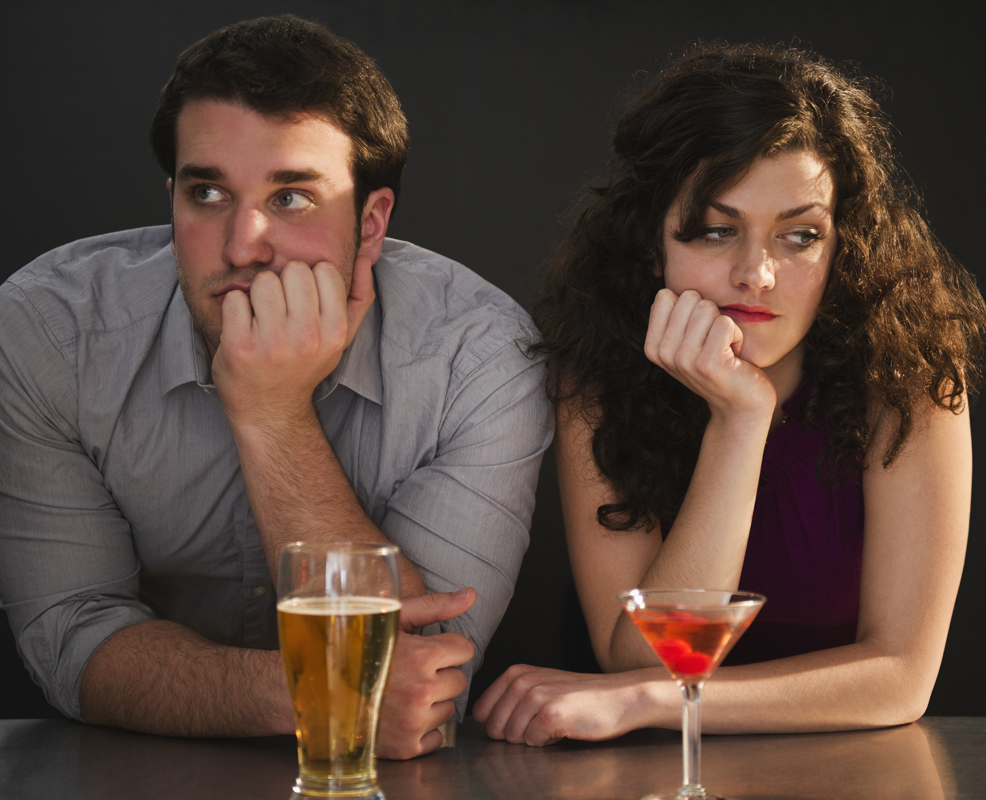 two people at a bar looking bored and annoyed