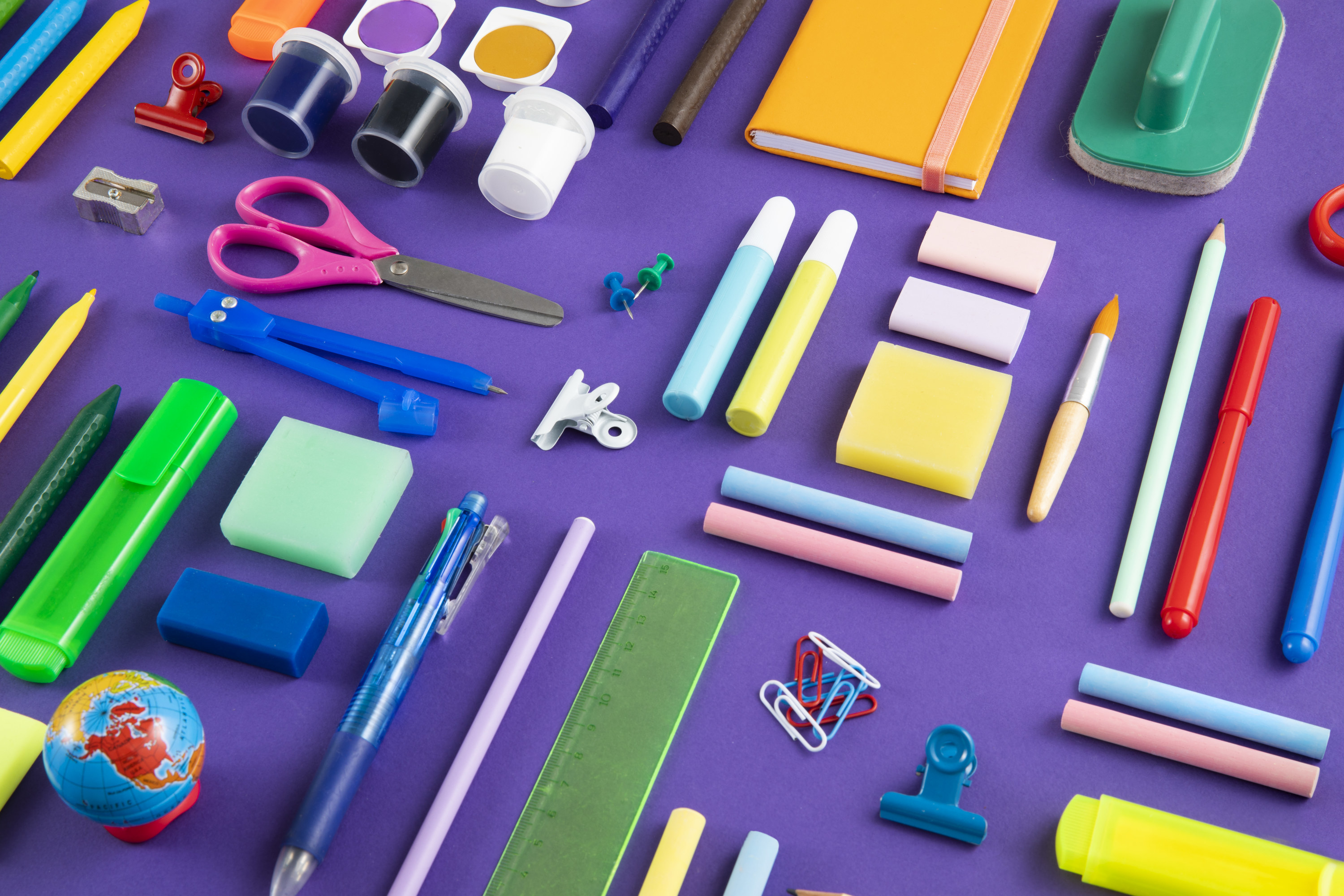 Large group of school supplies on purple background