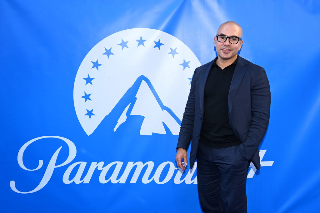 Chris standing in front of a sign with the Paramount logo which is the company&#x27;s name underneath an illustration of a mountain top within a semicircle of stars