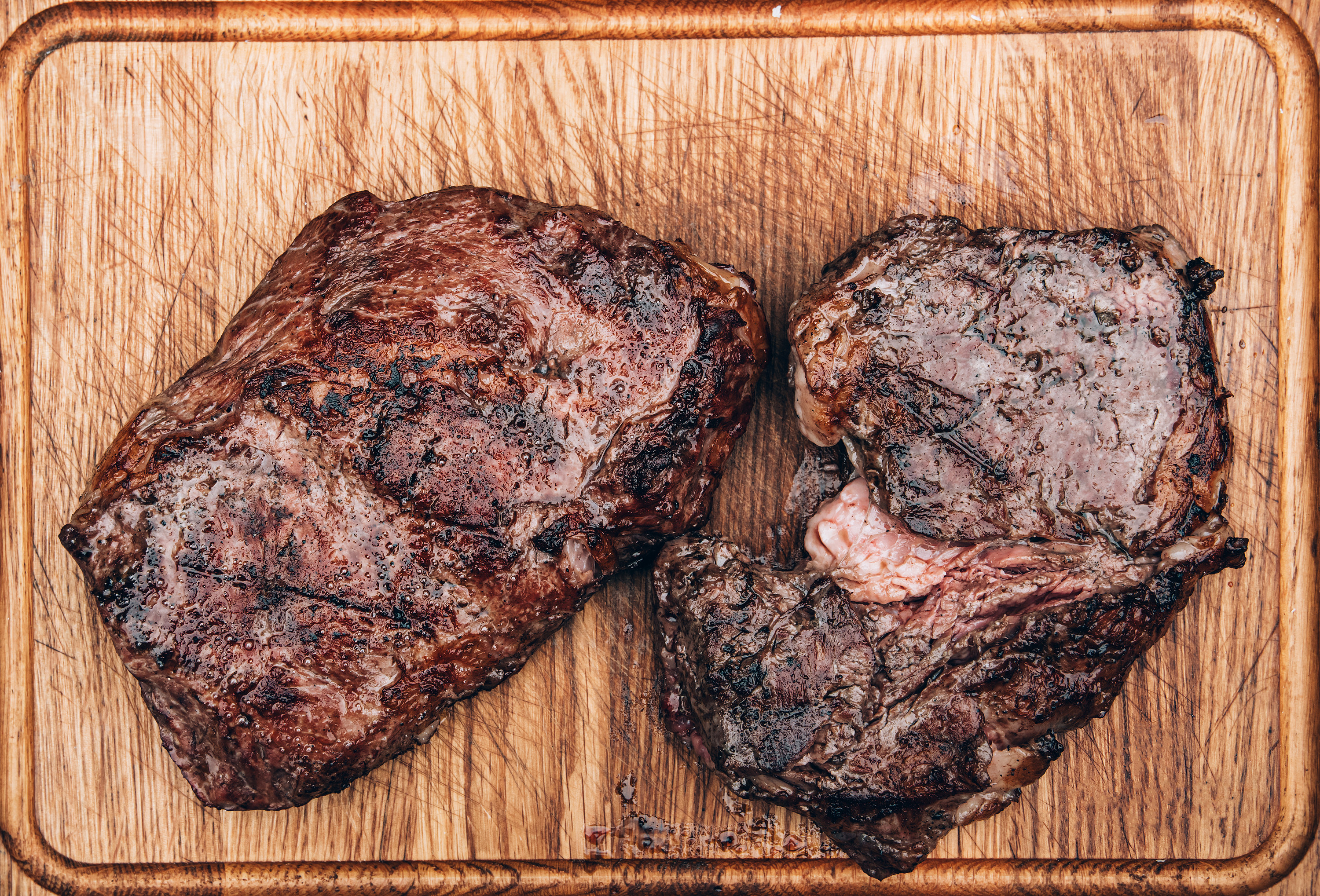Top view of two grilled beef meat steaks on wooden cutting board