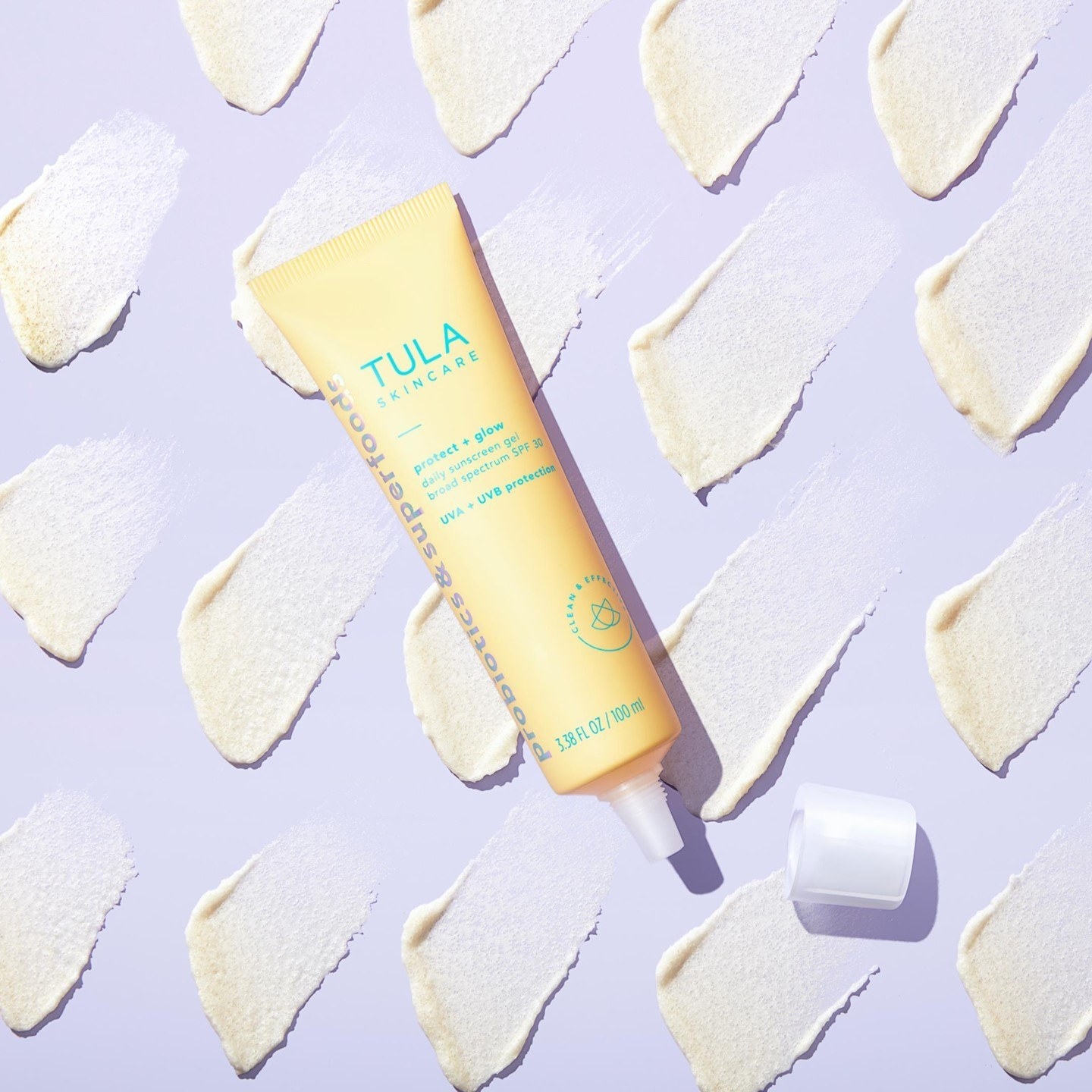 photo of the TULA sunscreen on purple background with product swatches