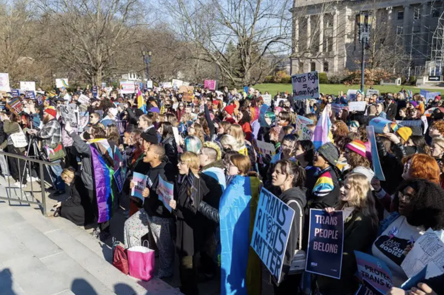 a crowd of protesters demonstrating against an anti trans bill outside a government building