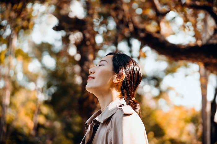 A woman with her eyes closed and her face turned up toward the sun