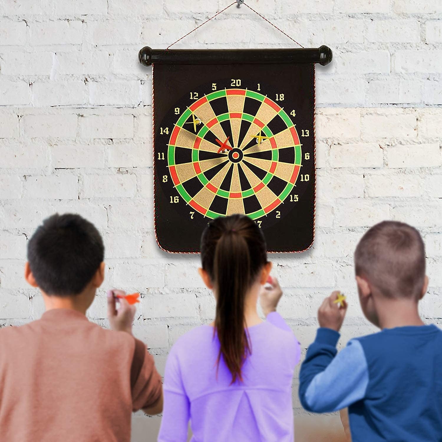 the dart board hung up and three kids about to throw darts at it