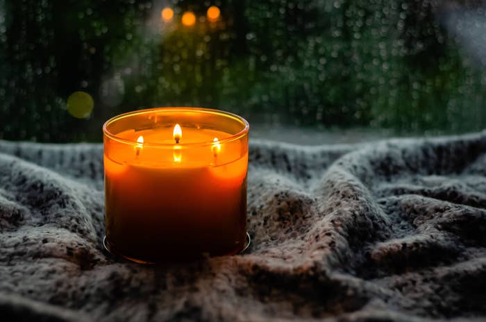 Close-up of a lit candle on a blanket